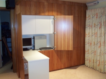 Fold down desk top behind two doors incorparting work station with seperate overhead cupboard inside.